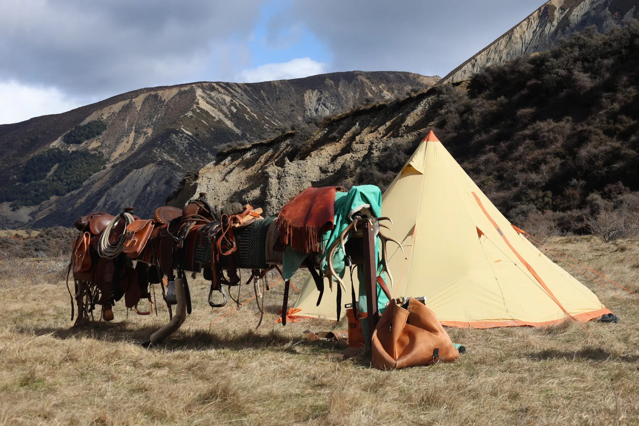 A canvas tipi camp beneath the mountains